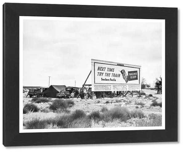 BILLBOARD CAMP, 1938. Three families camped behind a Southern Pacific Railway billboard on U. S. Highway 99 in California. Photograph by Dorothea Lange, 1938