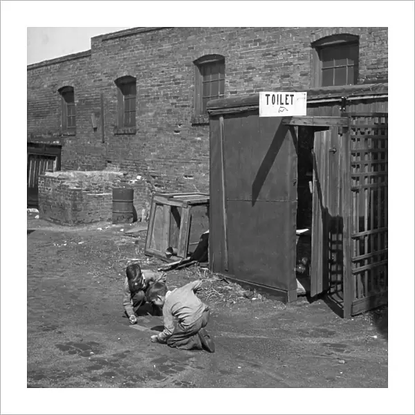 MARBLE GAME, 1936. Two boys playing marbles, next to an outhouse in St. Louis, Missouri