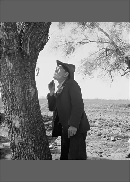 MIGRANT WORKER, 1939. A migrant worker shaving by the roadside, on his way to San Diego