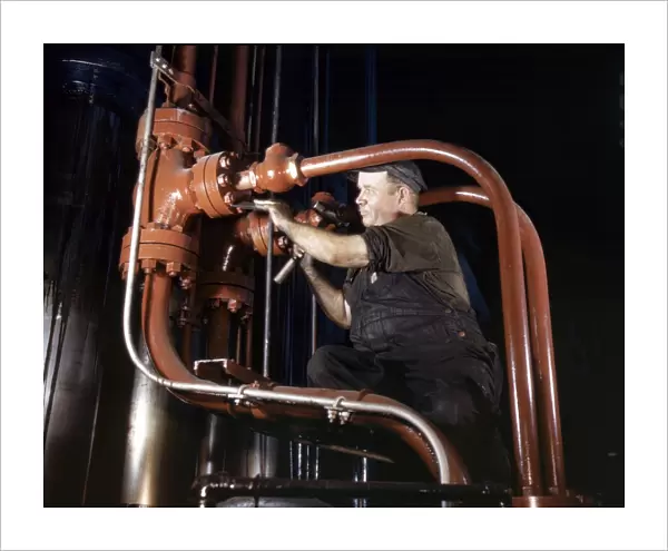 STEEL HYDRAULIC PRESS, 1942. Maintenance man working on a cold steel hydraulic