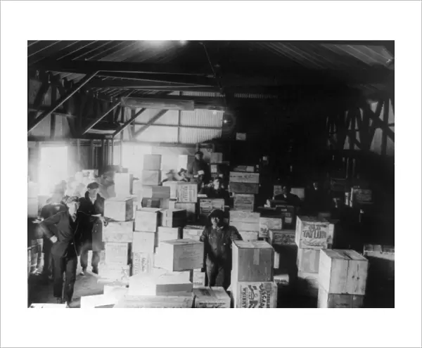 BOOTLEG LIQUOR, 1920s. Men standing in a warehouse filled with cases of confiscated moonshine