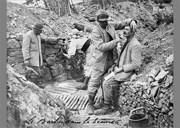 TRENCH BARBER. A French barber shaving a soldier in a trench. Photograph not dated