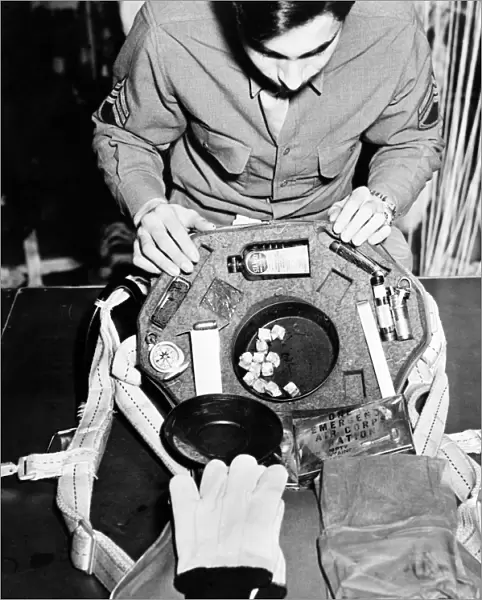 WWII: SOLDIER, c1943. American soldier Tony Gaudiello inspecting a kit containing