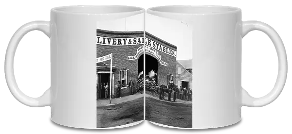John C. Howards livery stable and saloon on G Street in Washington, D. C. where John H. Surratt, a conspirator in the Abraham Lincoln assassination, kept horses before leaving town on 1 April 1865. At right is a horse drawn hose reel belonging to the Northern Liberties Fire Company. Photographed in 1865