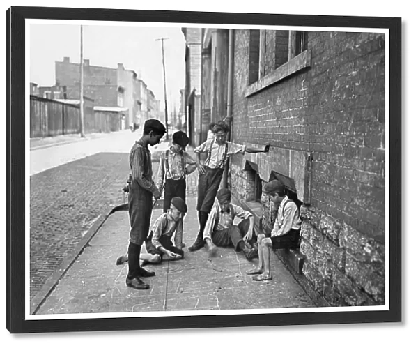 Group of boys gambling with dice on the sidewalk of Cincinnati, Ohio. Photograph by Lewis Hine, c1908