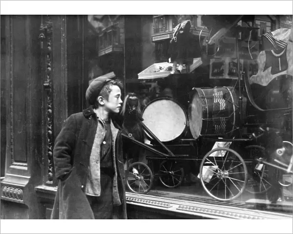 A boy looking at Christmas toys in a shop window. Photograph, early 20th century