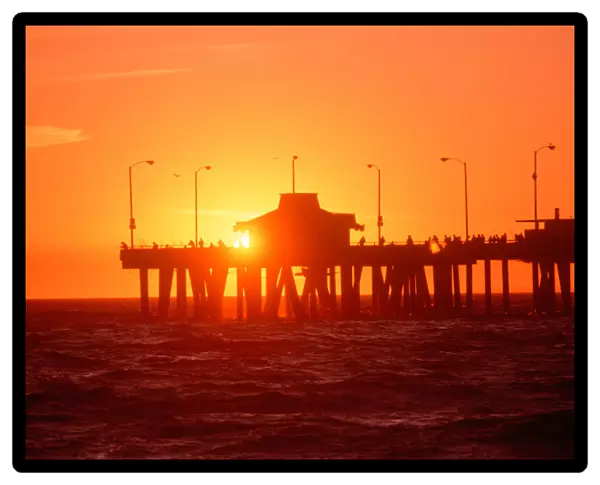 Silhouetted fishermen on Venice Pier at sunset, California