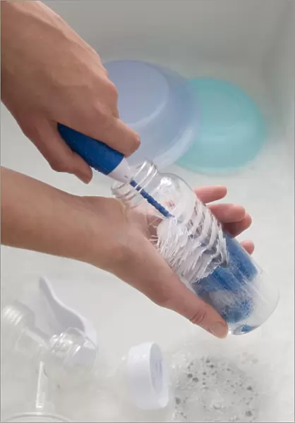 Hand scrubbing inside of baby bottle with a bottle brush, close-up