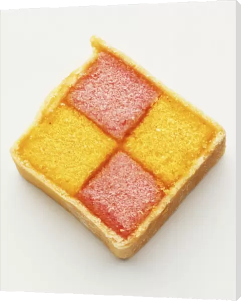 Square slice of iced pink and yellow sponge Battenburg cake, close up