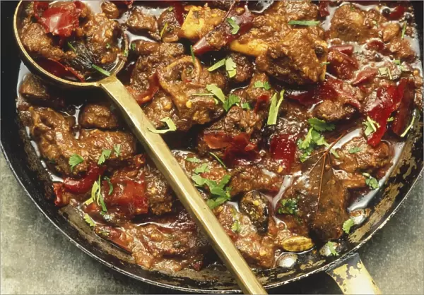Laal mass, lamb and chilli stew in a large frying pan, with a spoon, view from above