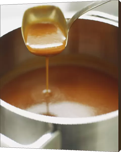 Brown sauce being ladled out of saucepan, close up