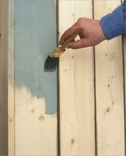 Wooden planks being painted grey with a brush
