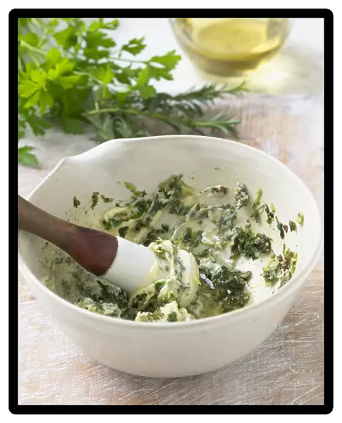 Preparing parsley and butter coating in bowl, using pestle, close-up