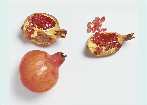 Punica granatum, whole Pomegranate and opened sections of fruit revealing seeds