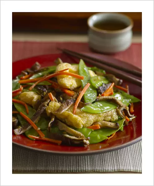 Deep fried tofu with vegetables, including shiitake mushrooms, snow peas, strips of carrots, served with soy sauce