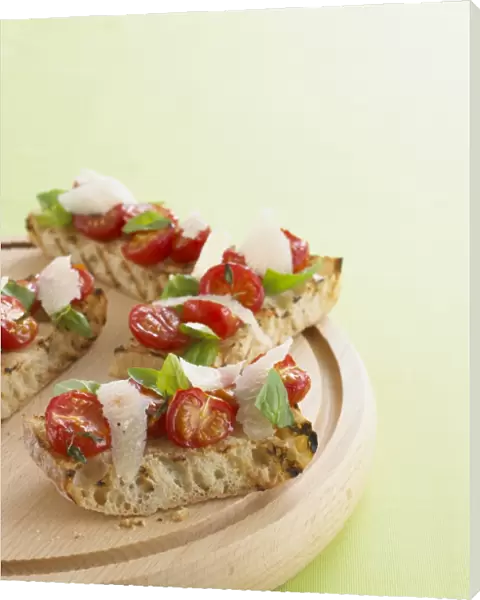 Tomato bruschetta with parmesan shavings and basil leaves, on chopping board, close-up