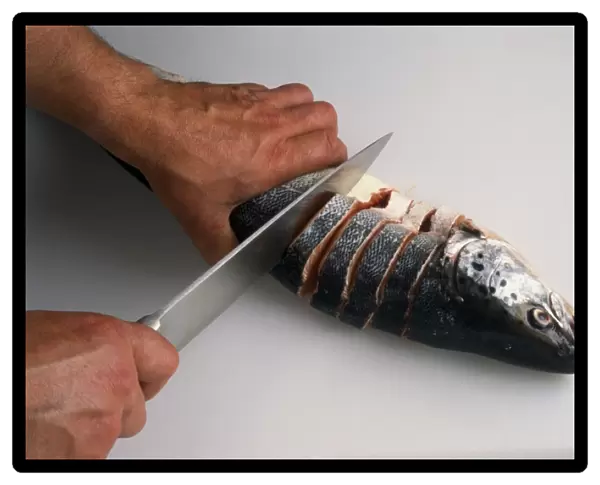 Using kitchen knife to cut salmon into steaks