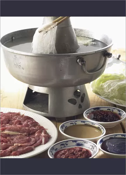 Mongolian hotpot, thinly sliced lamb, vegetables, and noodles in boiling water, served with array of sauces