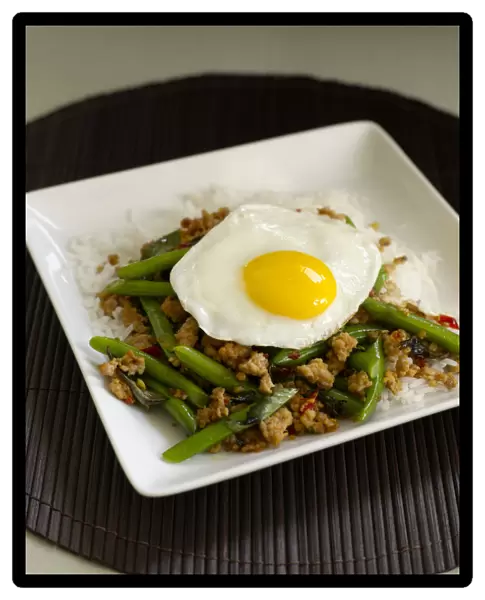 Pad kaprao gai, stir-fried spicy chicken with green beans, Thai basil and topped with fried egg