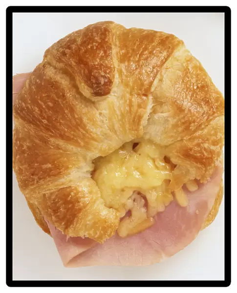 Above view of croissant filled with grated cheddar cheese and ham