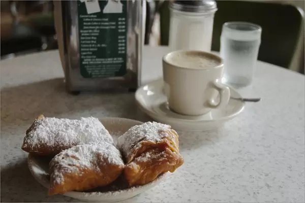USA, Louisiana, New Orleans, Cafe du Monde, cup of espresso coffee next to icing sugar-dusted pastries on a table