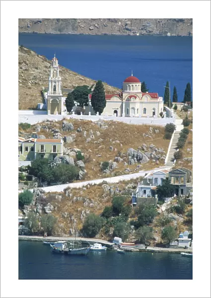 Greece, Dodecanese islands, Saegean, rocky hillside with church, boats moored, blue sea in foreground and background