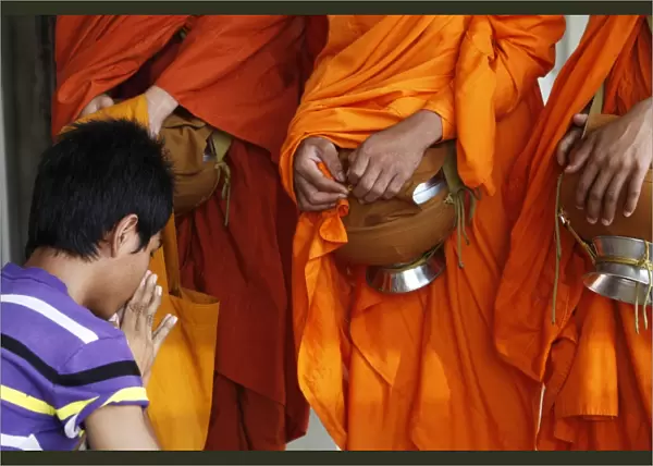 Man praying after giving alms to monks