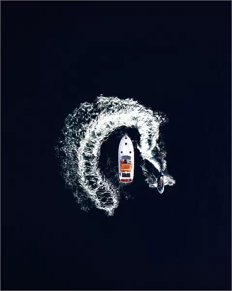 Aerial view of a jet ski swirling around a recreational boat