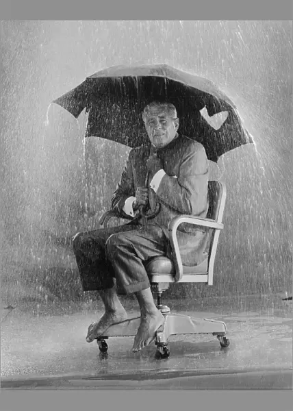 Mature man holding torn umbrella in rain