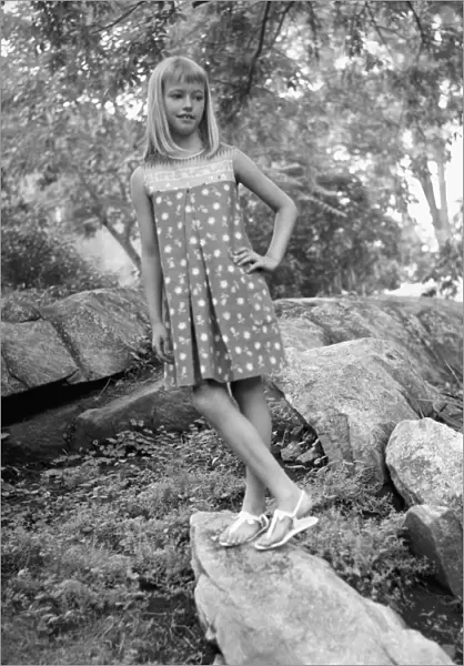 Girl (12-13) standing on boulder in forest, (B&W)