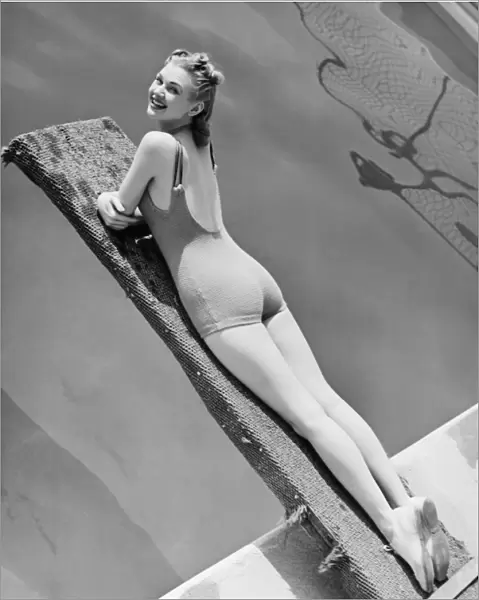 Woman lying on diving board (B&W), elevated view, portrait