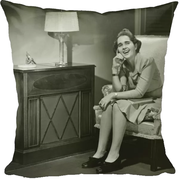 Woman sitting in armchair, smiling, (B&W)