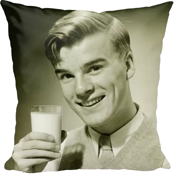 Young man holding glass of milk, smiling, (B&W), portrait