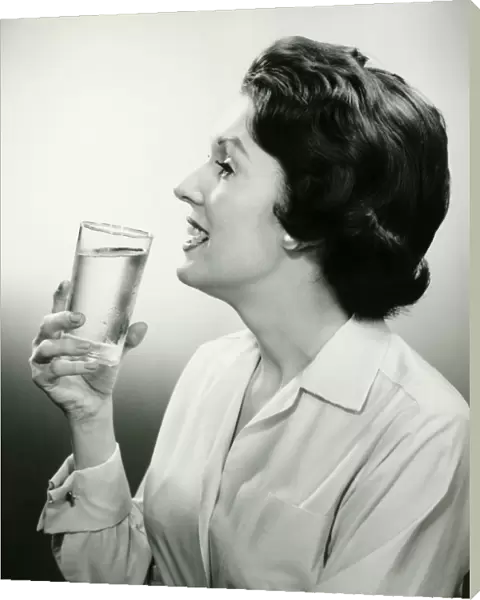 Woman holding glass of water, posing in studio, (B&W), (Portrait)