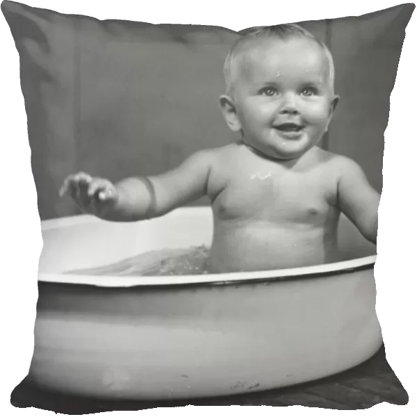Baby boy (6-9 months) bathing in basin (B&W)