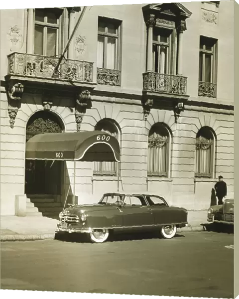 Car standing in front of hotel entrance, (B&W)
