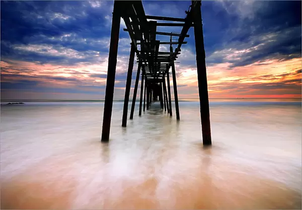 Seascape with old broken pier against dramatic sky
