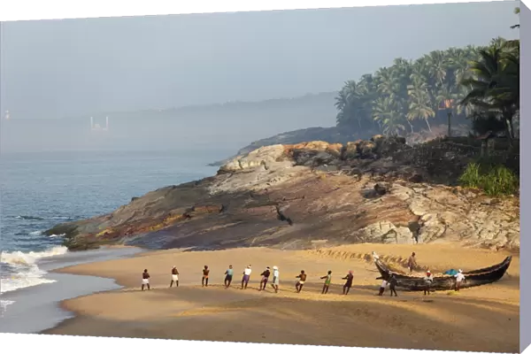 Fishermen pulling in a net, beach south of Kovalam, Vizhinjam in the distance, Malabar Coast, Malabar, Kerala, southern India, India, Asia