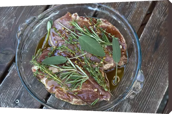 Pork neck steaks in marinade with herbs