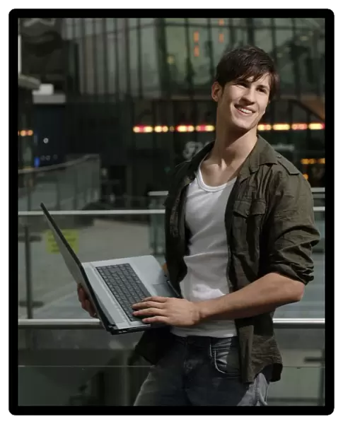 Student holding a laptop computer, smiling