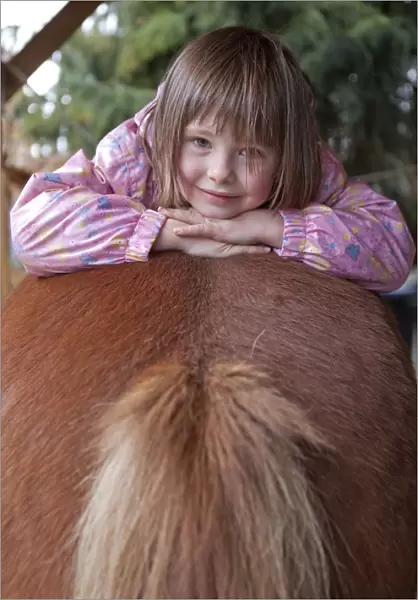 Young girl lying on a pony