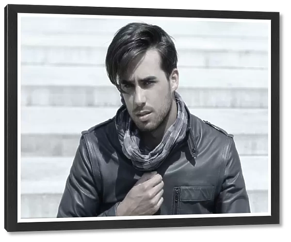 Young man wearing a leather jacket in front of an open staircase, portrait of a young rocker