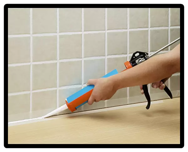 Hands applying sealant to tiles with sealant tube