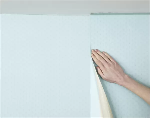 Person smoothing wall paper onto a wall