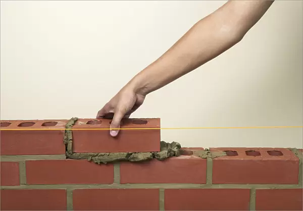 Placing a new brick on to fresh mortar on a wall