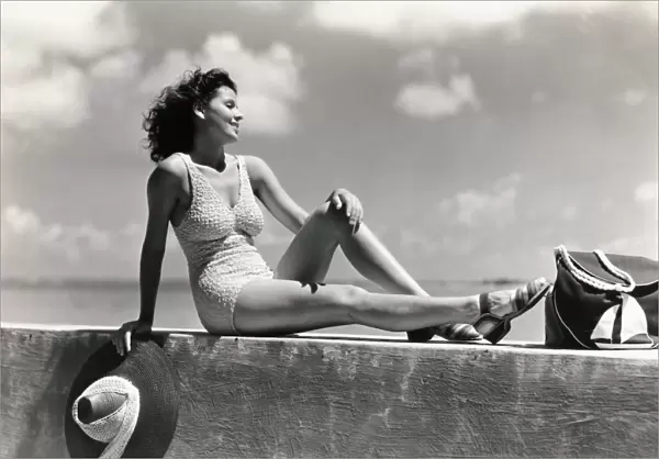 Young woman wearing knitted swimsuit, posing on wall by ocean. (Photo by H. Armstrong Roberts  /  Retrofile  /  Getty Images)