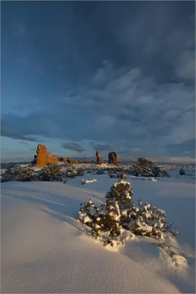 Snow covered landscape and reaching clouds near Balanced Rock, Arches National Park, Utah, USA