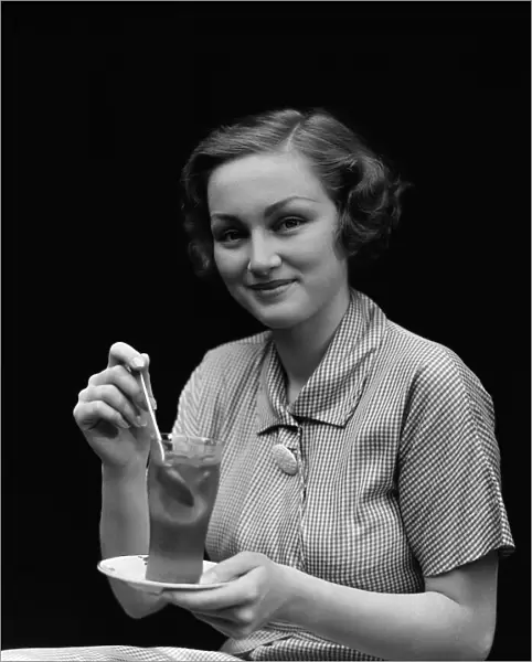Woman in checked dress, stirring a glass of iced tea, portrait