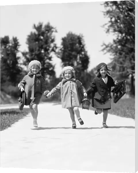 Three girls running along suburban sidewalk wearing fall weather coats and hats