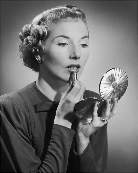 A woman applying her lipstick with the aid of a powder compact, circa 1955. (Photo by H. Armstrong Roberts / Retrofile / Getty Images)
